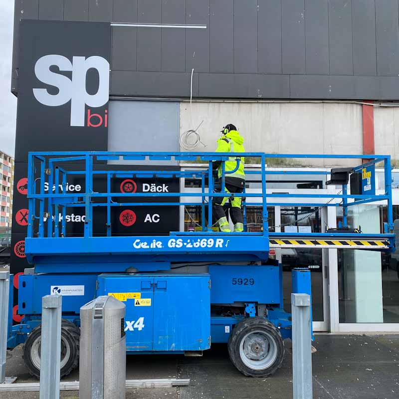 Skyltar Kungälv – Brightsigns montör monterar en fasadskylt med saxlift